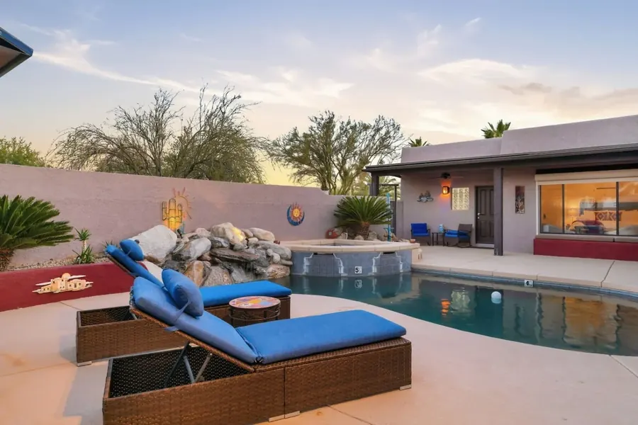 Pool patio with lounge chairs, rock fountain and house